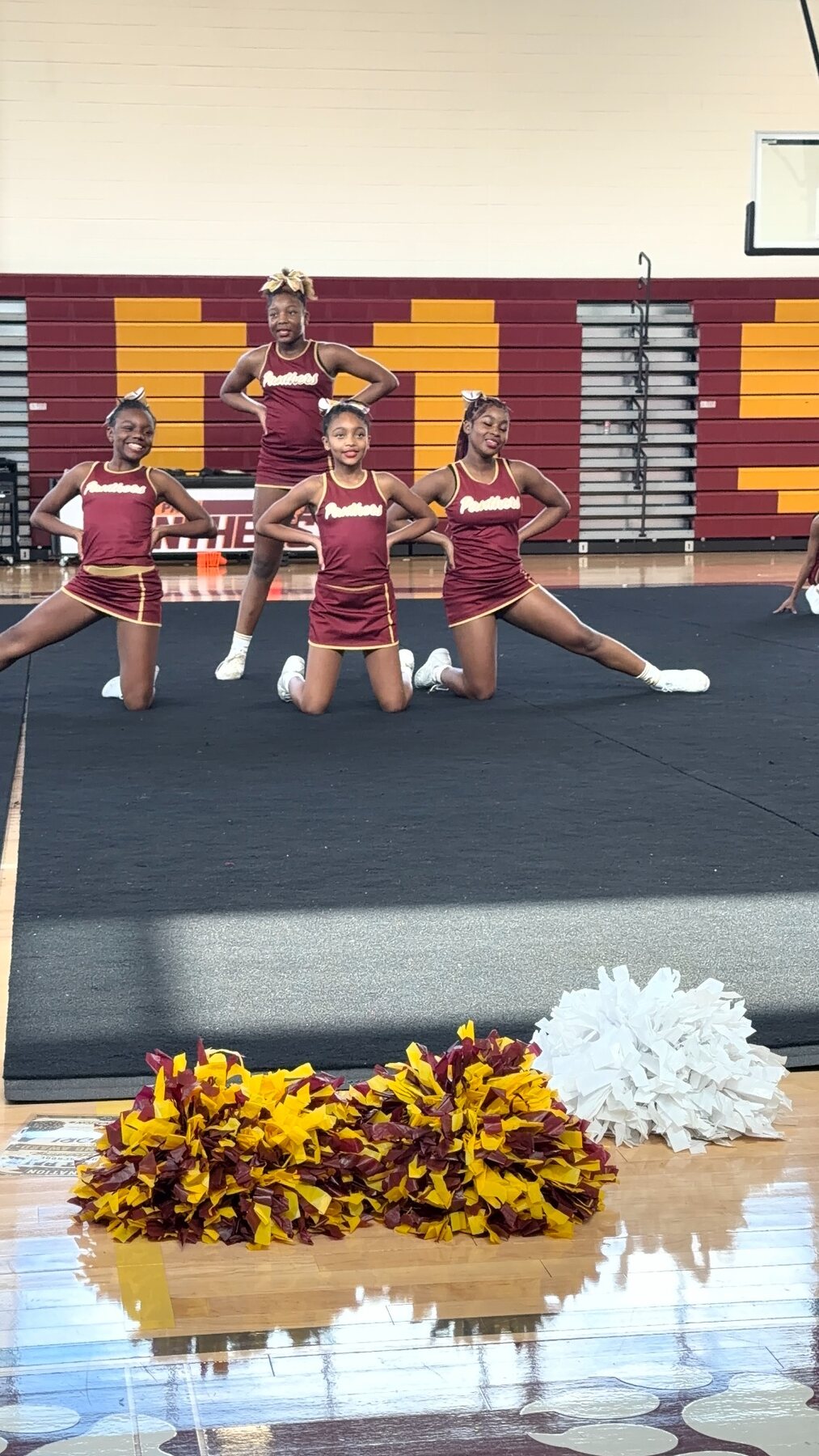 Cheer athletes performing in coordinating maroon and gold uniforms