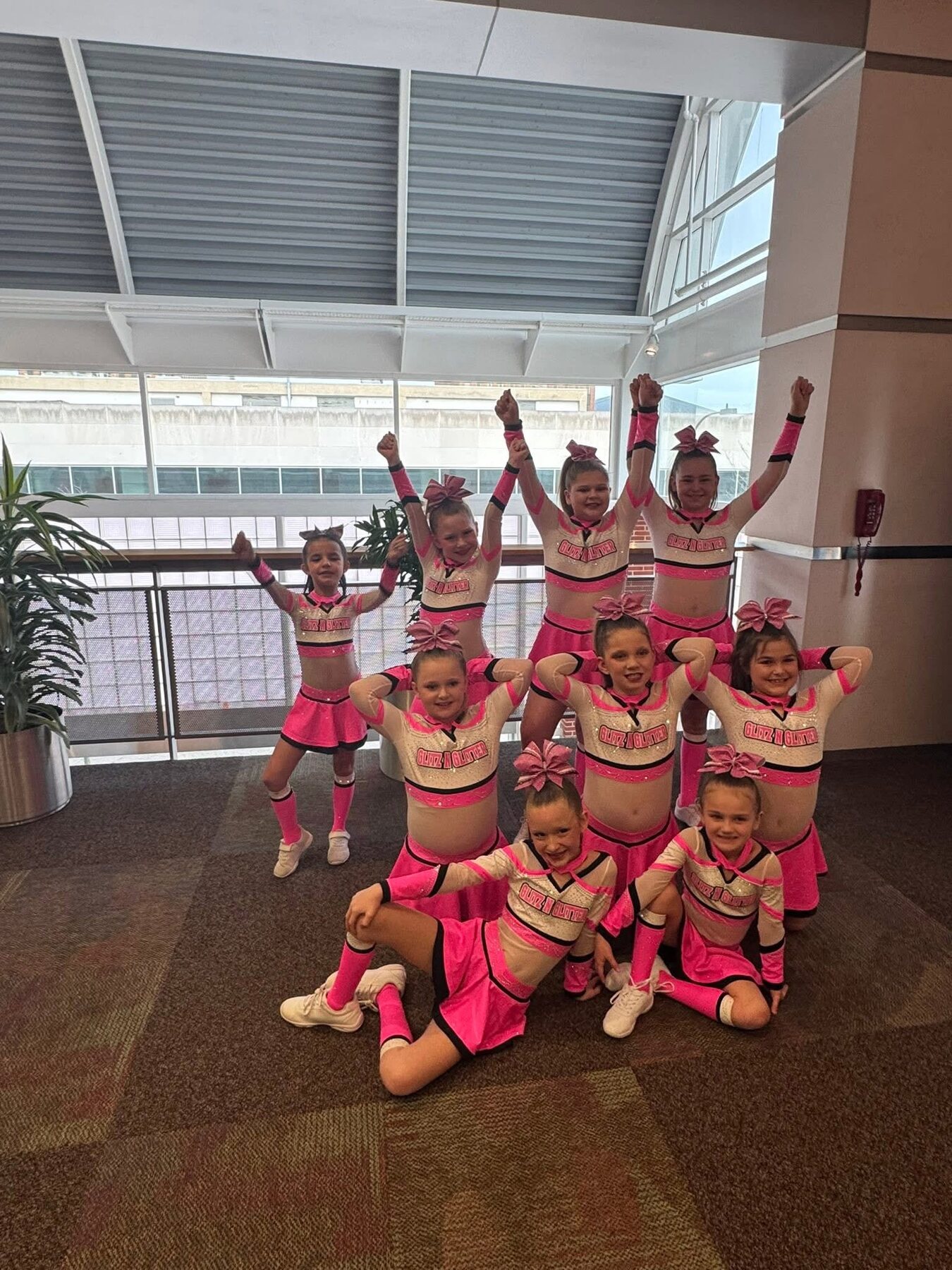 Youth cheer team posing together in matching hot pink, white, and black uniforms